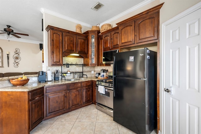 kitchen with stainless steel gas range oven, light tile patterned flooring, visible vents, freestanding refrigerator, and tasteful backsplash