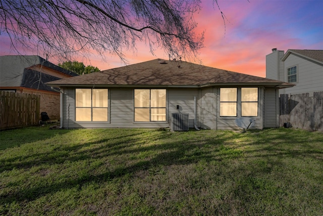 rear view of house with a lawn, fence, and central air condition unit