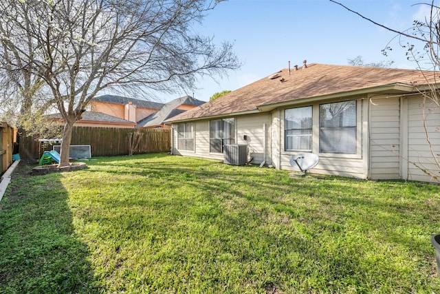 rear view of property featuring a fenced backyard, a lawn, and central AC