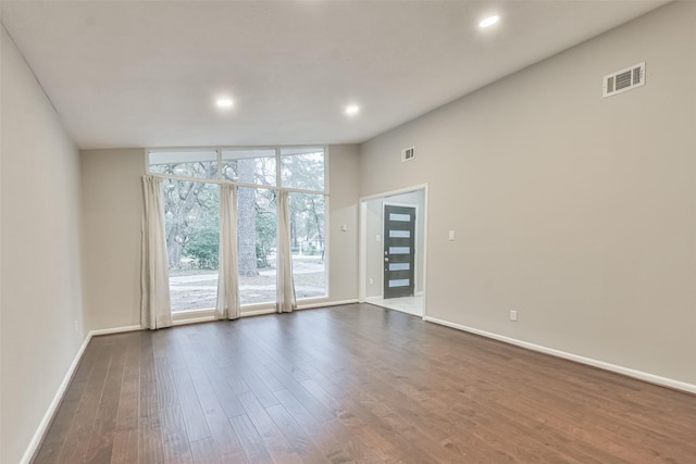 unfurnished room featuring baseboards, dark wood-type flooring, visible vents, and floor to ceiling windows