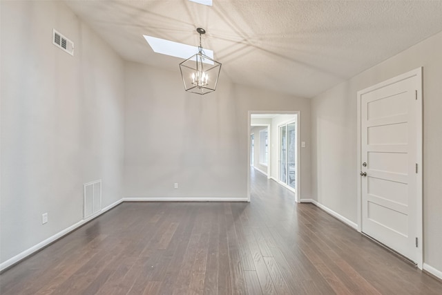 unfurnished dining area featuring dark wood-style floors, vaulted ceiling with skylight, visible vents, and baseboards