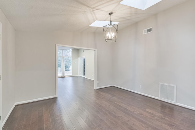 unfurnished room featuring baseboards, vaulted ceiling with skylight, visible vents, and dark wood-style flooring