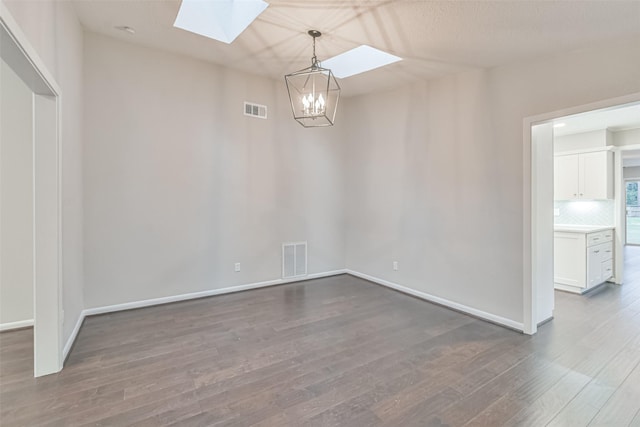 interior space featuring a skylight, visible vents, baseboards, and wood finished floors