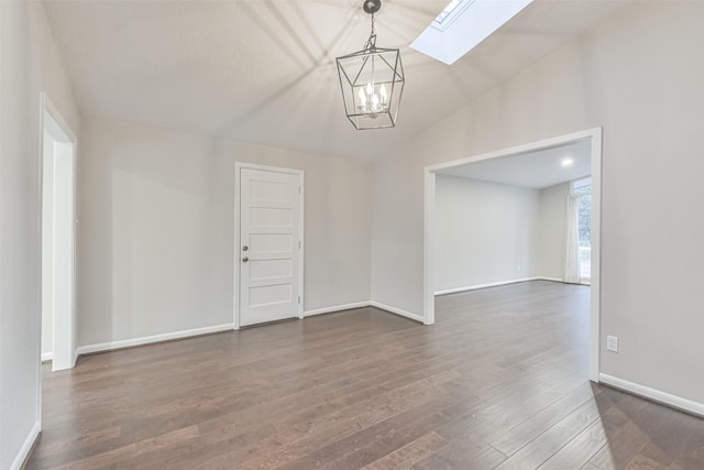 spare room featuring vaulted ceiling with skylight, baseboards, dark wood finished floors, and a chandelier