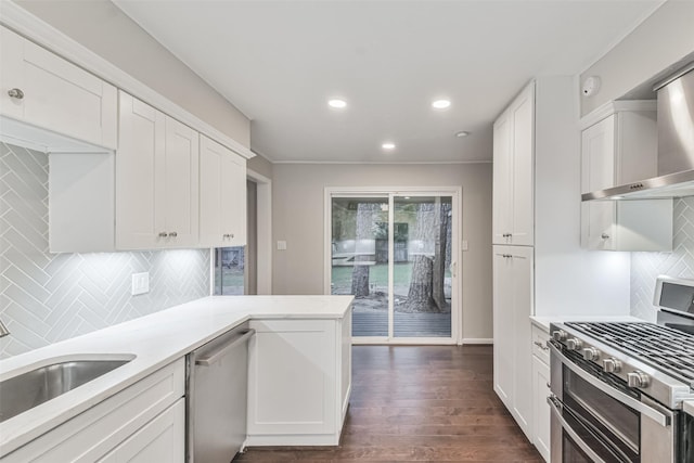 kitchen with wall chimney exhaust hood, appliances with stainless steel finishes, light countertops, and white cabinetry