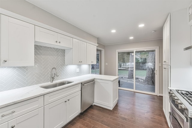 kitchen featuring dark wood-style floors, tasteful backsplash, appliances with stainless steel finishes, white cabinets, and a sink