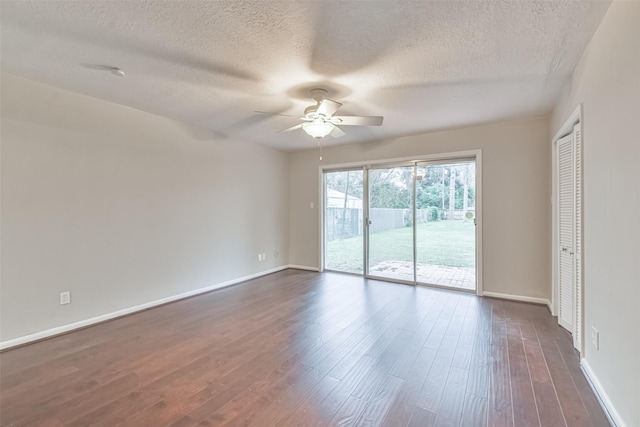 empty room featuring dark wood-type flooring, a ceiling fan, and baseboards