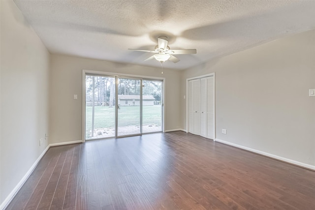 unfurnished room featuring dark wood-type flooring, a textured ceiling, baseboards, and a ceiling fan