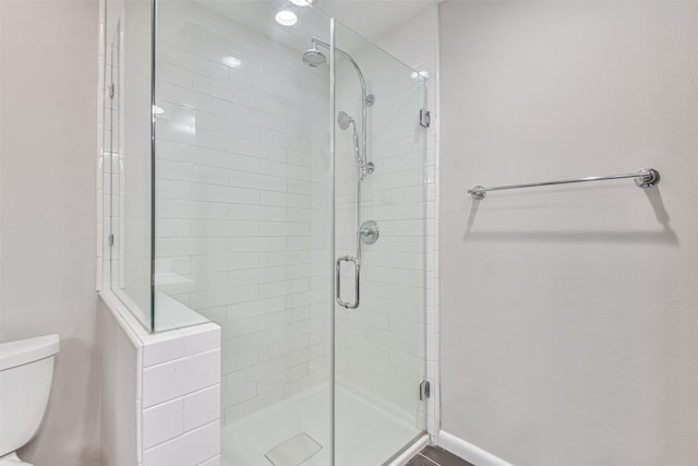 full bathroom with toilet, a shower stall, and baseboards