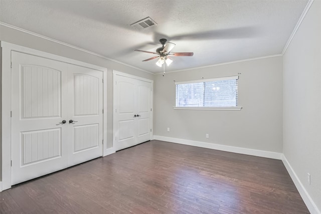 unfurnished bedroom featuring a textured ceiling, wood finished floors, visible vents, and crown molding