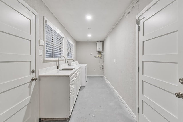 washroom with a textured wall, a sink, baseboards, water heater, and washer / dryer