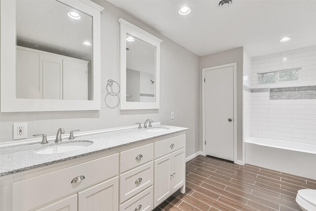 bathroom featuring wood tiled floor, a sink, recessed lighting, and double vanity