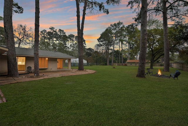 yard at dusk featuring a patio, an outdoor fire pit, and fence