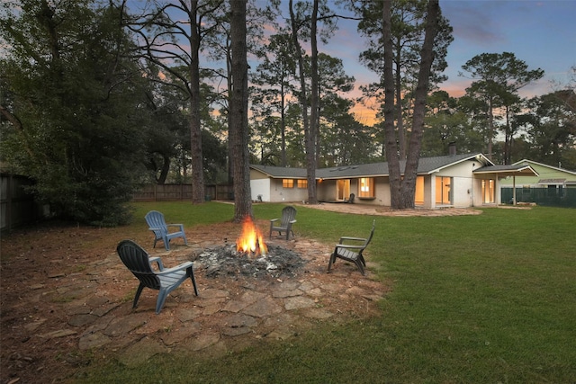 rear view of property featuring a chimney, fence, a fire pit, and a yard