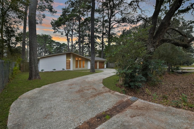 view of front of home featuring a lawn, fence, and concrete driveway