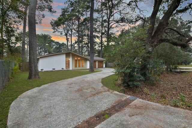 view of front facade featuring driveway, a front lawn, and fence