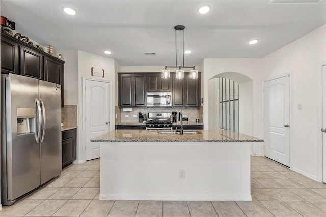 kitchen with arched walkways, stainless steel appliances, visible vents, a sink, and light stone countertops