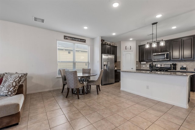 kitchen with visible vents, decorative backsplash, hanging light fixtures, light stone countertops, and stainless steel appliances