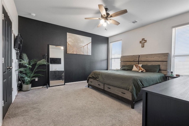 bedroom with a ceiling fan, light colored carpet, visible vents, and baseboards