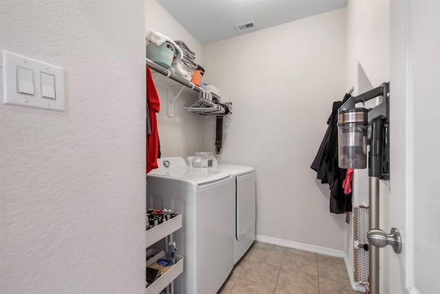 washroom featuring light tile patterned floors, visible vents, washer and dryer, laundry area, and baseboards