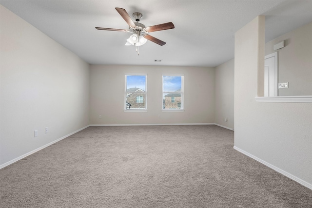 empty room featuring a ceiling fan, visible vents, carpet floors, and baseboards