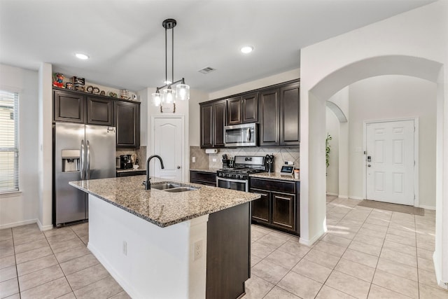 kitchen with stainless steel appliances, visible vents, backsplash, a sink, and light stone countertops