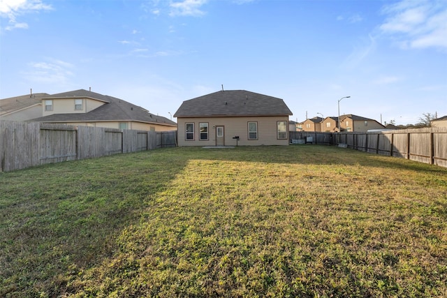 back of property featuring a fenced backyard and a yard