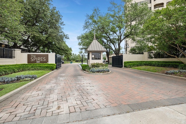 view of decorative road with curbs, a gate, and a gated entry