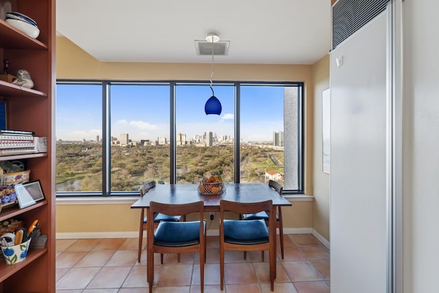 dining area with a view of city, light tile patterned flooring, visible vents, and a wealth of natural light