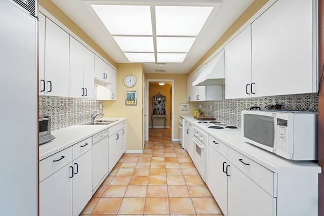 kitchen featuring under cabinet range hood, white appliances, tasteful backsplash, and a sink