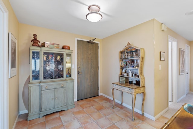 foyer entrance with light tile patterned floors and baseboards