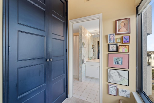 hallway featuring light tile patterned floors and a sink