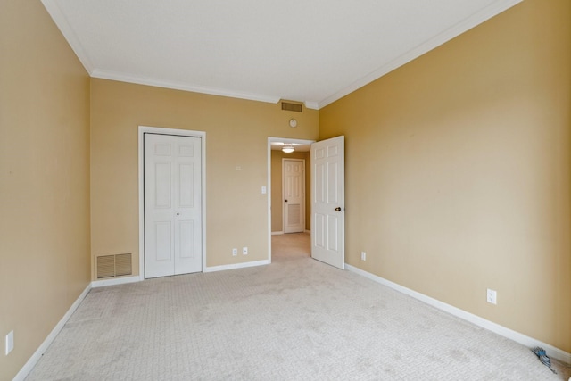 unfurnished bedroom featuring carpet flooring, ornamental molding, baseboards, and a closet