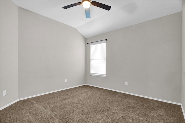 spare room with vaulted ceiling, a ceiling fan, dark colored carpet, and baseboards