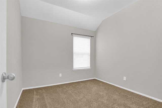 carpeted spare room with baseboards and vaulted ceiling