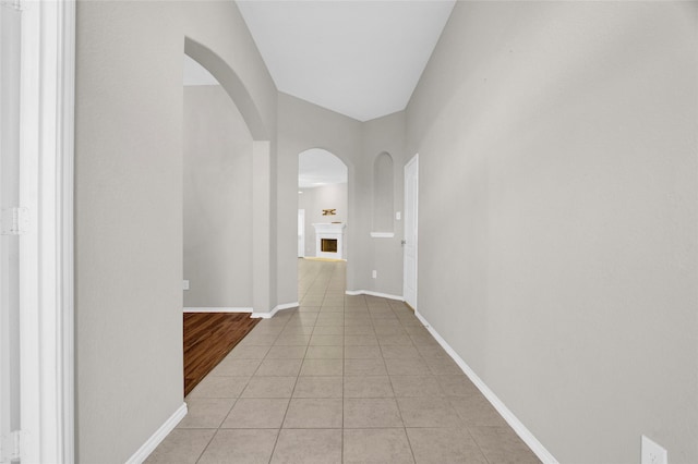 hall featuring light tile patterned floors and baseboards