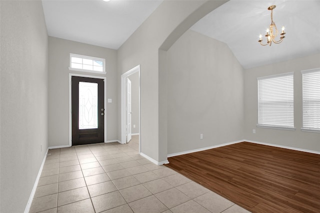 foyer entrance with light wood-style floors, a healthy amount of sunlight, arched walkways, and baseboards