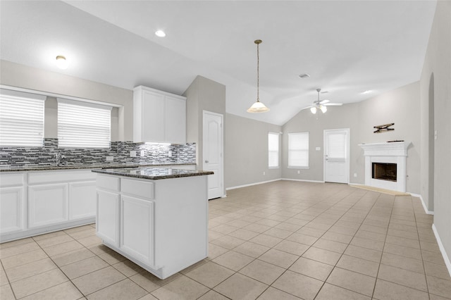 kitchen with light tile patterned floors, a ceiling fan, lofted ceiling, a fireplace, and tasteful backsplash