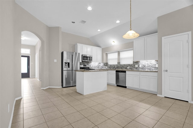 kitchen with visible vents, arched walkways, appliances with stainless steel finishes, tasteful backsplash, and a center island