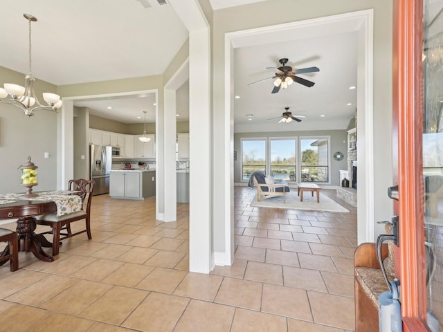 dining area with a notable chandelier, light tile patterned floors, a fireplace with raised hearth, visible vents, and baseboards