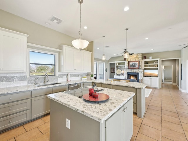 kitchen with a center island, visible vents, a ceiling fan, open floor plan, and a sink