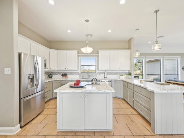 kitchen with a peninsula, a kitchen island, stainless steel refrigerator with ice dispenser, and backsplash