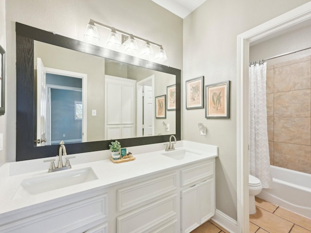 full bath featuring toilet, double vanity, a sink, and tile patterned floors