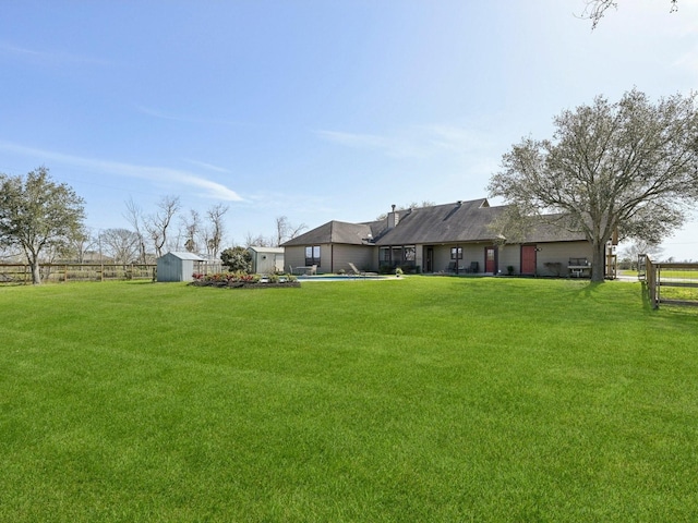 view of yard with a storage unit, a swimming pool, an outdoor structure, and fence