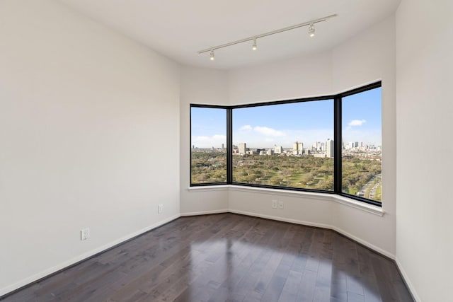 spare room with baseboards, dark wood-type flooring, and a city view