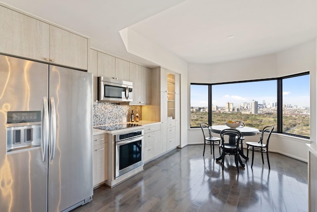 kitchen with stainless steel appliances, light countertops, dark wood-type flooring, a view of city, and tasteful backsplash