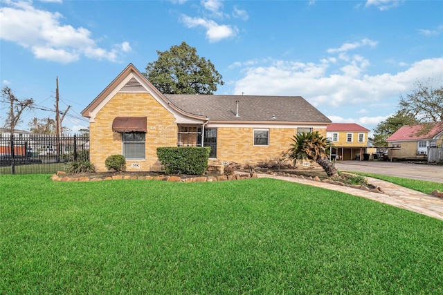 view of front of house featuring brick siding, a shingled roof, a front yard, and fence