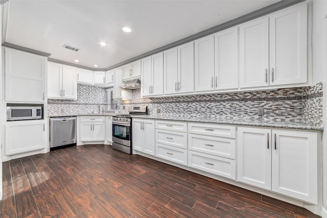 kitchen with visible vents, under cabinet range hood, backsplash, stainless steel appliances, and white cabinets
