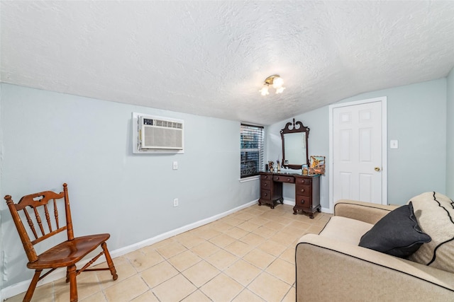 interior space featuring a wall mounted air conditioner, baseboards, a textured ceiling, and light tile patterned floors