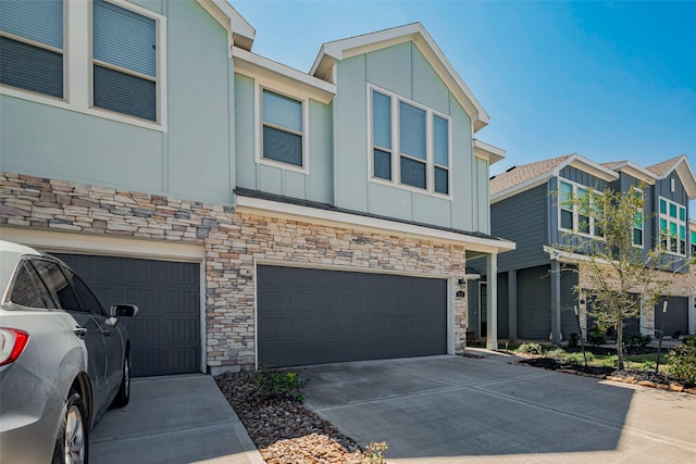 townhome / multi-family property featuring concrete driveway, a garage, board and batten siding, and stone siding